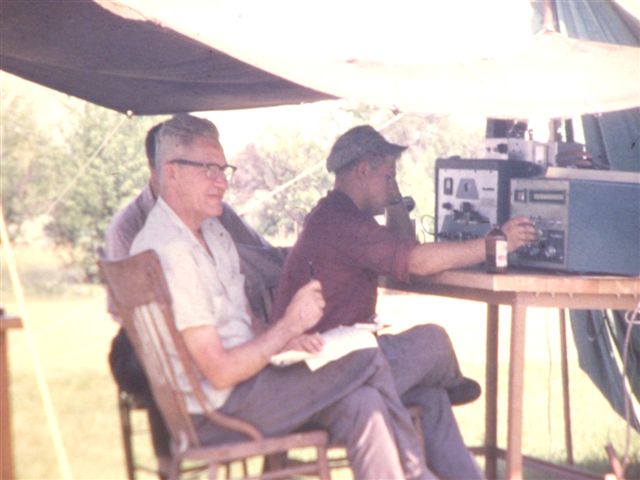 Front: SCM Jack Siringer, W8AJW who also appears in other photos, and a fine Elmer to many. The  photo was probably taken at the Field Day held in his back yard on Clague Rd.  The  operator is W8NNX,  the owner of the DX-100 and the Mohawk with homebrew TR switch atop the DX-100. Hiding in the back is Dave, K8GVK.